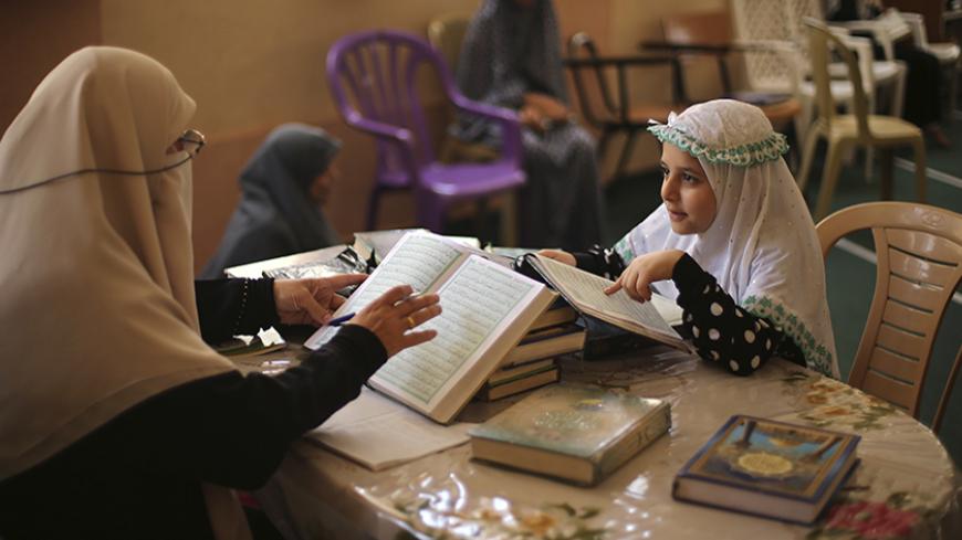 A Palestinian girl recites Koran to her teacher during a Koran memorization lesson on the first day of the holy fasting month of Ramadan at a mosque in Gaza City June 29, 2014.REUTERS/Mohammed Salem (GAZA - Tags: RELIGION SOCIETY EDUCATION) - RTR3W9WR